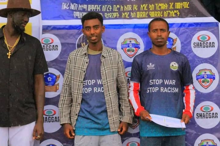 Club members standing in front of a competition backdrop, one holding a document