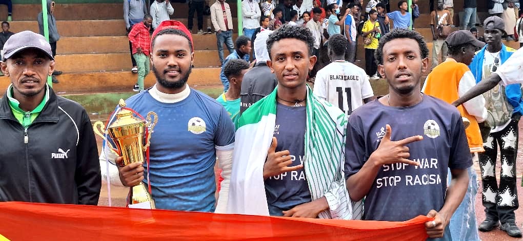 Club members posing together with a trophy at a football ground